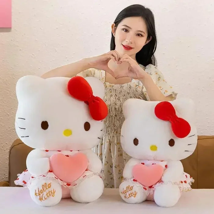 Smiling woman makes heart gesture with two Hello Kitty plush toys.