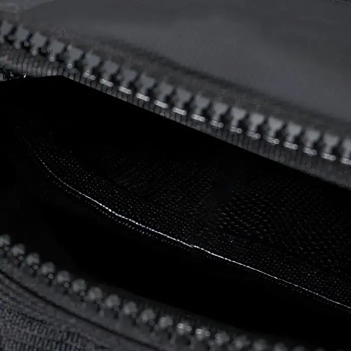 Macro shot of metal zipper on black fabric, showcasing the quality and durability of the sling bag's closure