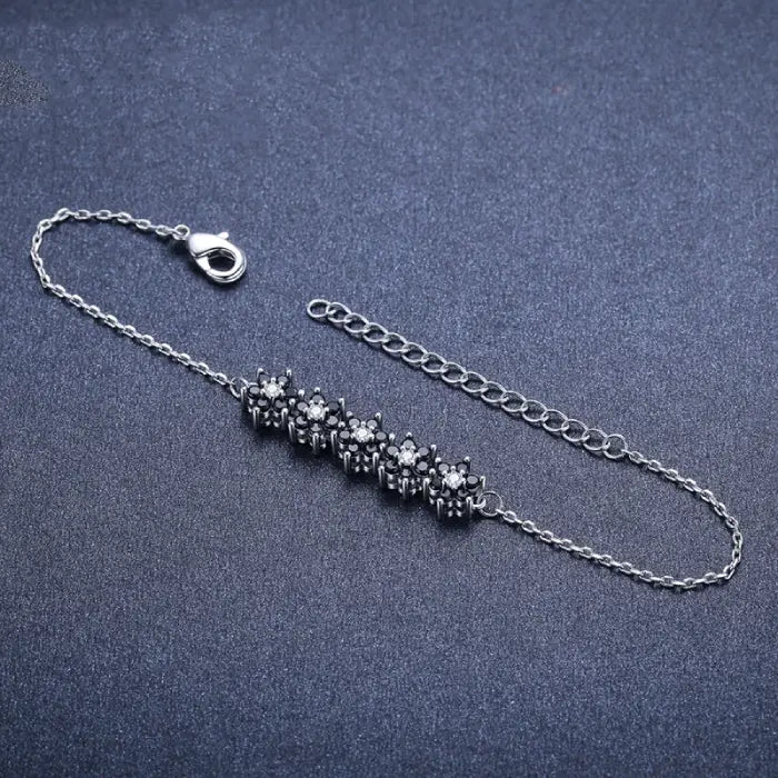 Adjustable silver bracelet with black floral detail, perfect for modern women’s jewelry collections.