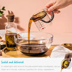 Adjustable measuring cup pouring thick syrup into a glass bowl on a kitchen counter.