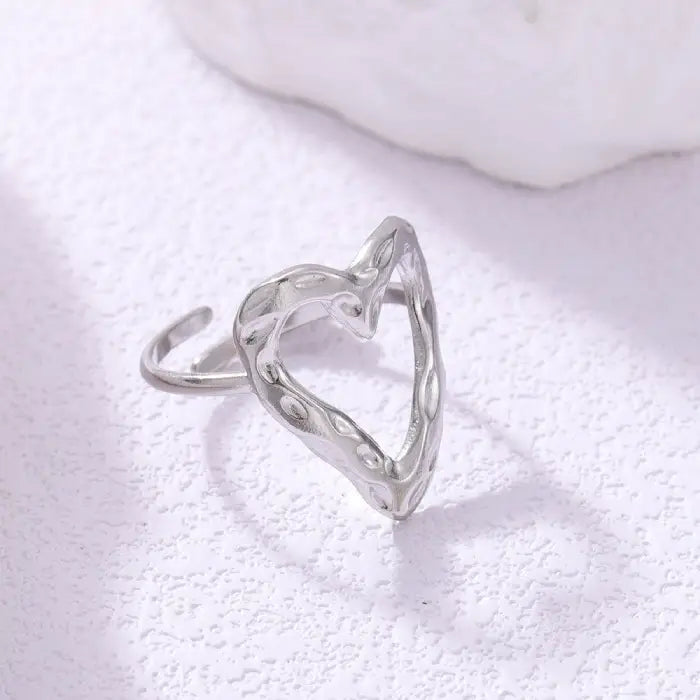adjustable open heart ring in silver with hammered texture displayed on bright surface, offering a minimalist modern jewelry style
