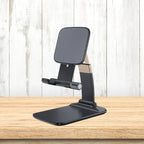 Adjustable phone stand in black displayed on wooden surface, showcasing stable modern support for phones with ergonomic functionality.