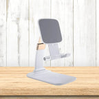 Adjustable phone stand in white placed on wooden table, offering stable ergonomic device support with a clean minimalist design.
