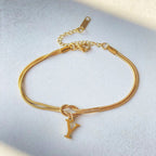 Gold bracelet with a 'Y' charm on a light gray background