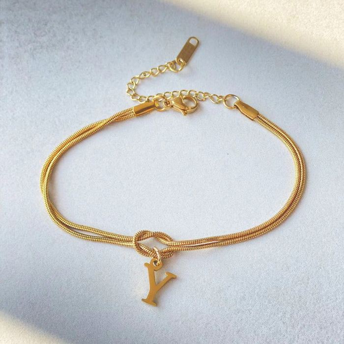 Gold bracelet with a 'Y' charm on a light gray background