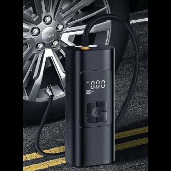 Black portable air compressor with digital display next to a silver alloy car wheel on asphalt road with yellow markings