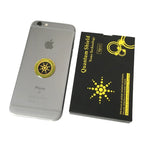 Anti radiation sticker on silver iPhone beside black and yellow quantum shield packaging.