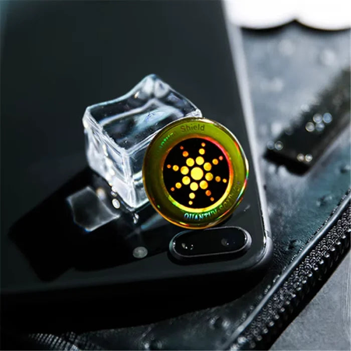Anti radiation sticker on black phone near ice cube reflecting light and placed on textured surface.