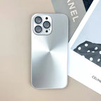 Silver anti smudge iPhone case with brushed metallic look on beige desk next to fashion magazine.
