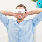 Smiling man relaxing with Anti-Wrinkle Eye Massager in a modern office setting.