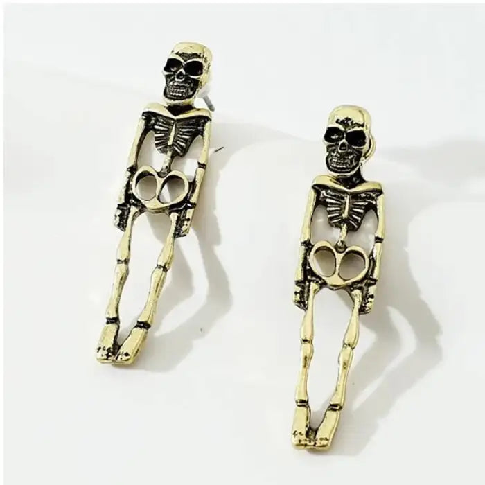 Antique-style gold skeleton earrings laid flat with full-body design and heart-shaped hip bones.