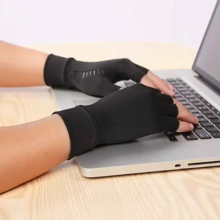Arthritis Gloves worn while typing on a laptop to provide compression and hand support.