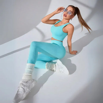 Athletic two-piece set in turquoise ribbed fabric with white leg warmers and chunky sneakers, studio photography with dramatic shadows