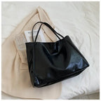 Autumn Shoulder bag in glossy black leather finish placed on cream blazer and book