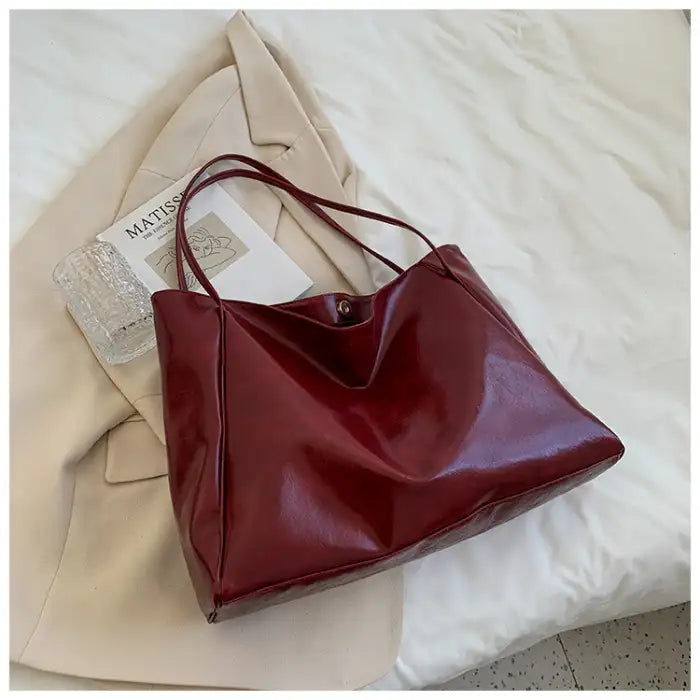 Autumn Shoulder bag in wine red glossy faux leather styled on bed with magazine and blazer