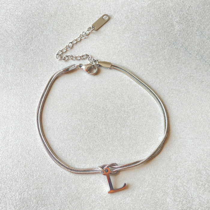 Silver bracelet with a letter 'L' charm on a light gray background