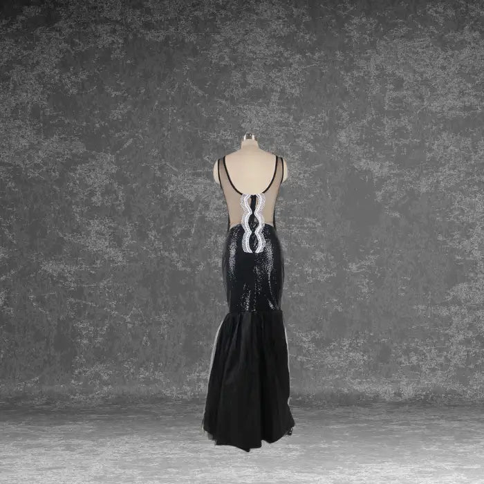 Rear view of the black sequin mermaid dress on a mannequin, showing the sheer back panel with white lace detail