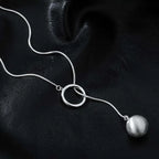 ball loop chain necklace elegant silver loop pendant with ball charm on black surface