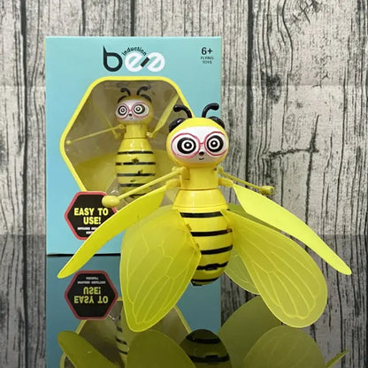 Flying bee robot toy shown with retail packaging box featuring easy-to-use product messaging and age recommendation details