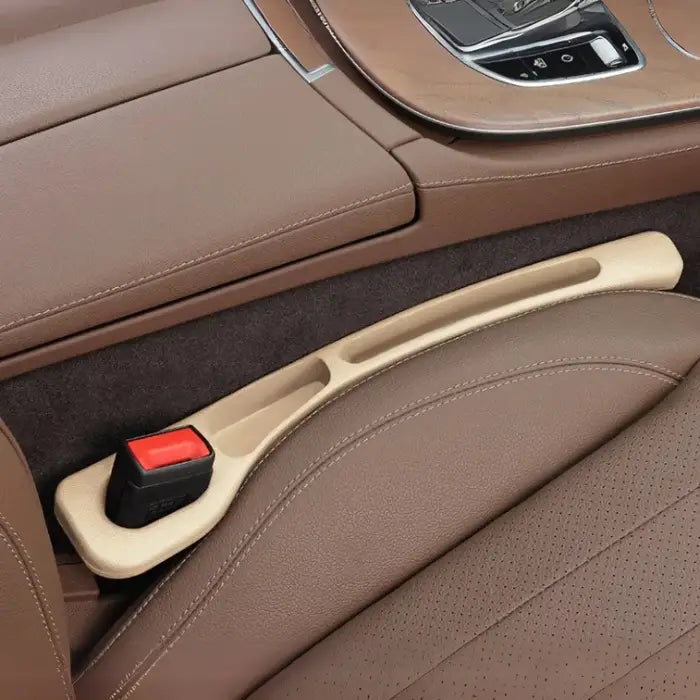 Beige plastic car seat gap filler installed between brown leather seats with chrome console trim