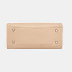 Bottom view of structured beige handbag showing protective metal feet and quality leather construction