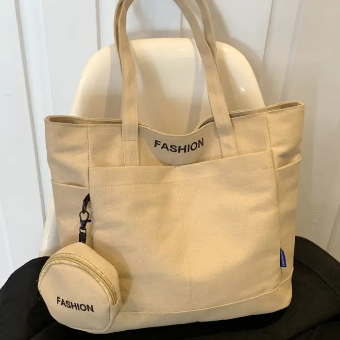 Beige tote bag with mini pouch labeled "Fashion," displayed elegantly on a white chair.