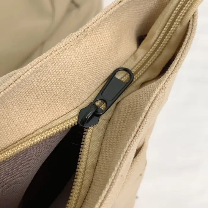 Close-up view of beige tote bag’s secure black zipper, highlighting its practical design and durability.