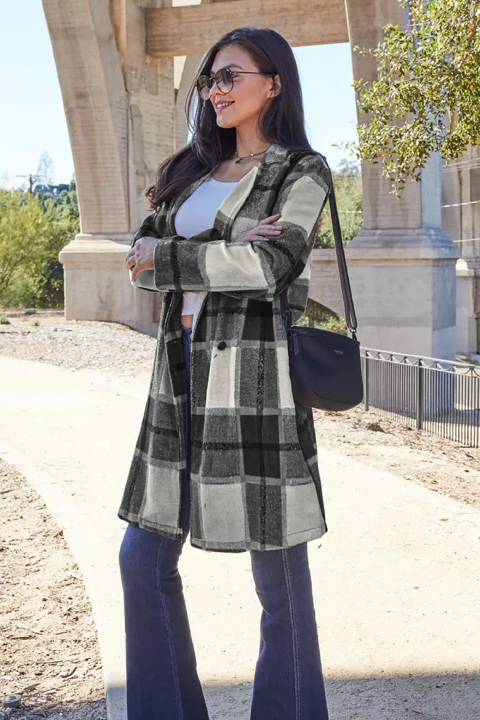 Side view of a woman in a black-and-white plaid wool coat paired with flared jeans and a black crossbody bag outdoors.