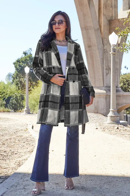 Woman wearing a black-and-white plaid wool coat styled with flared jeans, a white top, and sunglasses near an arched bridge.