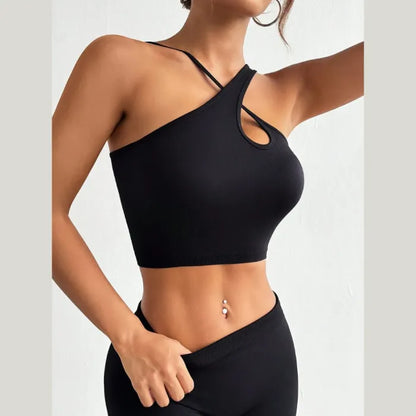 Woman taking selfie wearing black asymmetric crop top with cutout detail, showing toned midriff and navel piercing