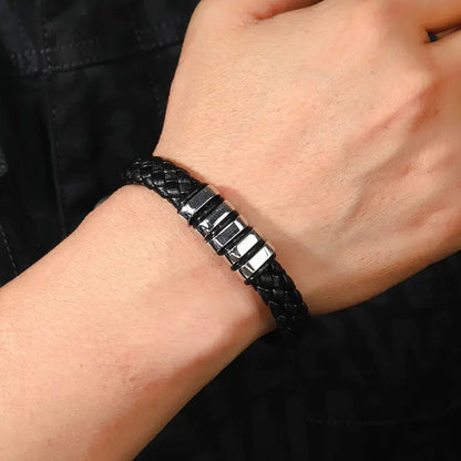 Black braided leather bracelet with silver accents worn on wrist, showcasing stylish men’s accessory design.