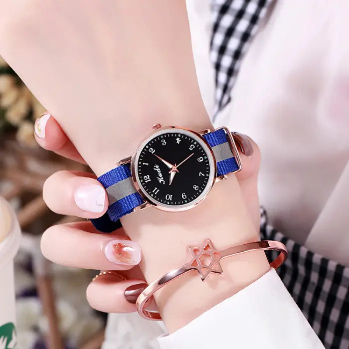 Women's watch with a black dial and blue strap, paired with a rose gold star bracelet.
