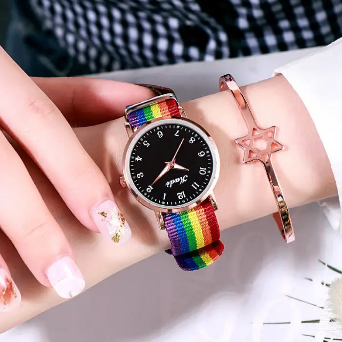 Women's watch with a black dial and rainbow strap, styled with a rose gold star bracelet.