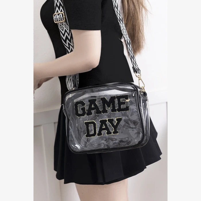 Fashion styling of clear stadium compliant bag with "GAME DAY" text worn with black dress and patterned shoulder strap