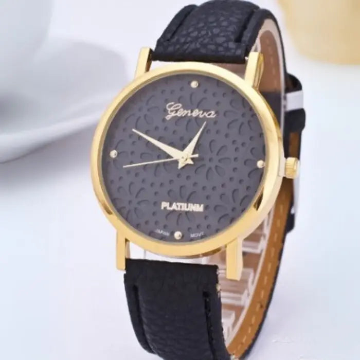 Black women's watch with a gold floral-patterned dial and black leather strap.