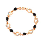 Black gemstone teardrop bracelet with gold heart accents, ideal for formal and chic occasions.