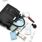 Black leather handbag with organized contents including phone, makeup, wallet, and tablet for daily use.