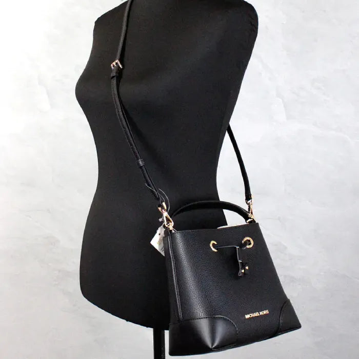 Black leather handbag with gold accents on a mannequin, showcasing luxury fashion accessory.