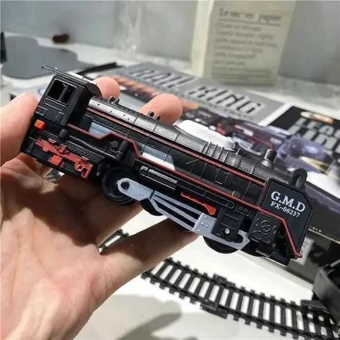 Hand holding a black locomotive from a toy train set with red and silver details.