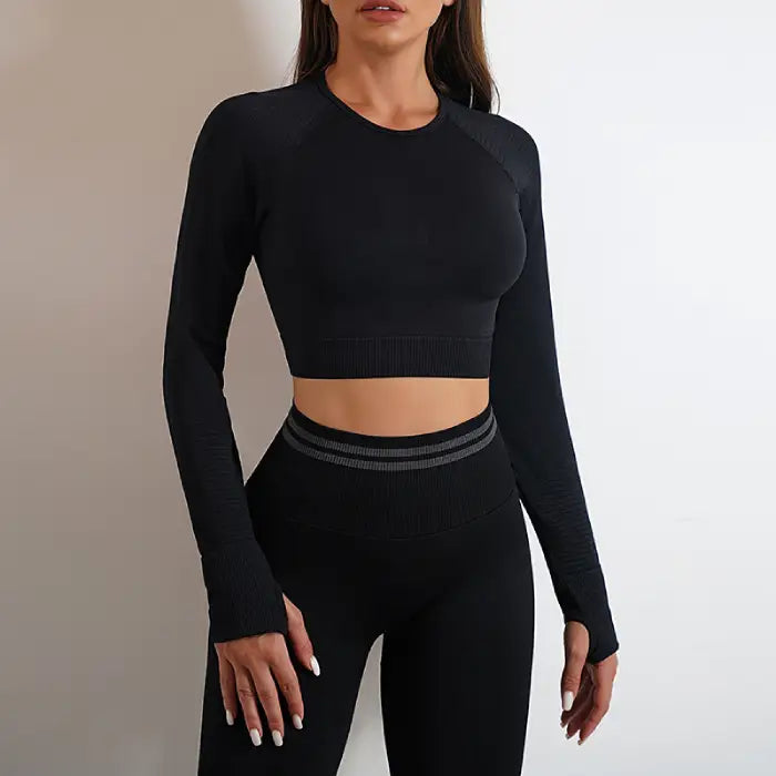  Women's seamless activewear in black with long-sleeve crop top and high-waisted yoga pants, front view.