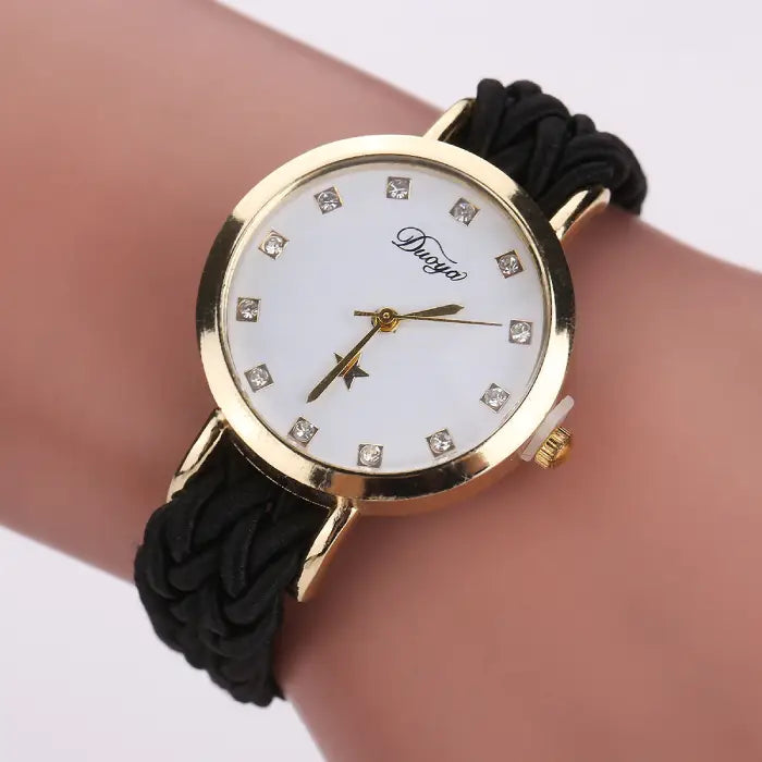 Women's watch with a gold case, white dial, and black braided rope band.