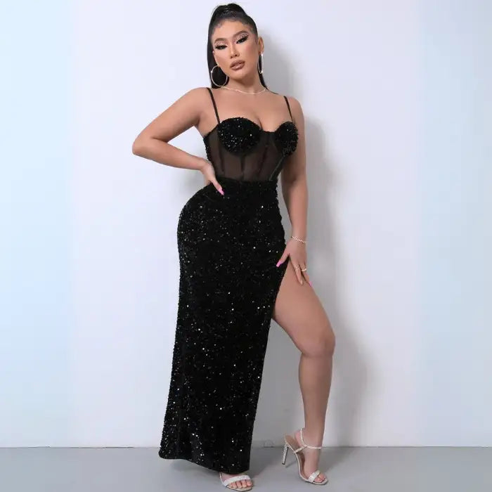 Black sequin dress with a sheer corset bodice, thigh-high slit, and spaghetti straps, styled for formal occasions.
