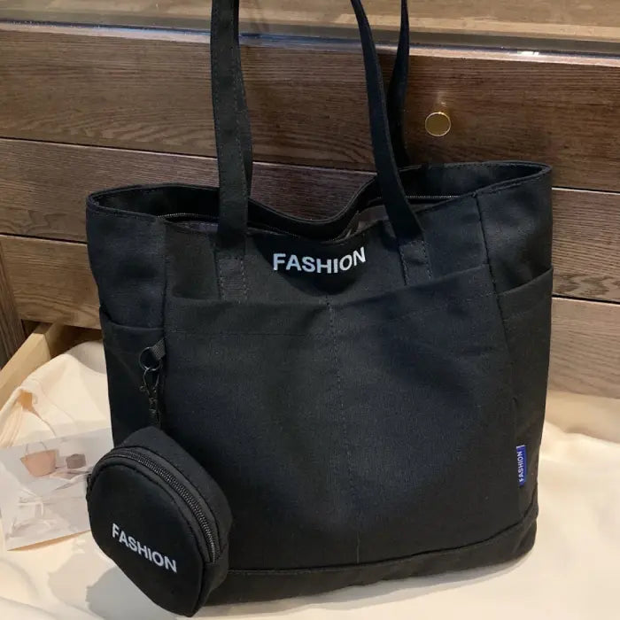 Black tote bag with mini pouch displayed on a wooden table, perfect for stylish and practical use.