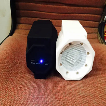 Black and white octagonal wireless speakers side by side on orange fabric, showing power indicators and speaker grilles