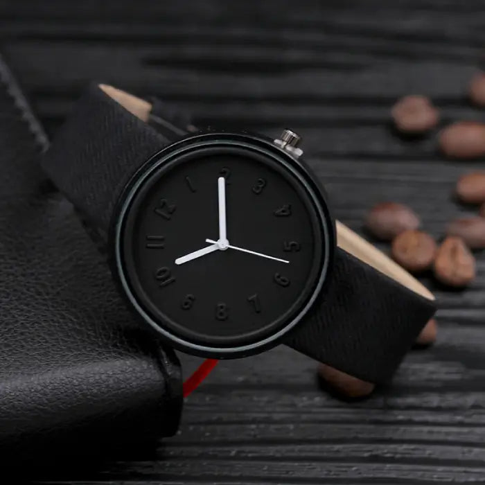 Elegant black wristwatch with minimalist embossed dial and white hands for a sleek, modern look.