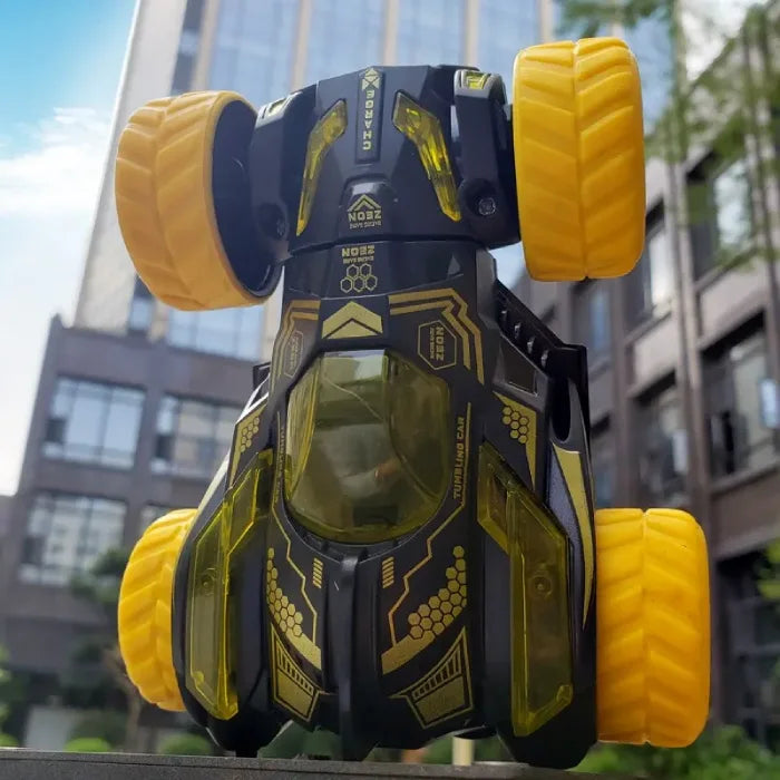 Black and yellow stunt car displayed upside down against a modern building background, highlighting durability.