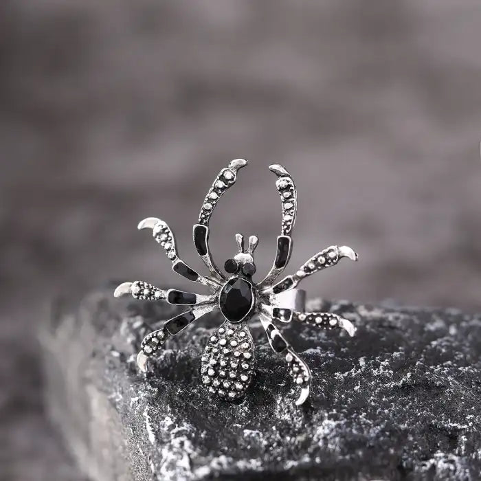 Blackwidow Spider rings with silver engraved legs and black gem body displayed on rock