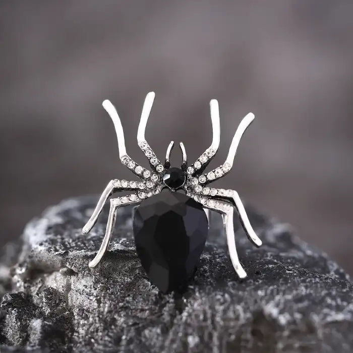 Blackwidow Spider rings with silver legs and faceted black gemstone on textured stone
