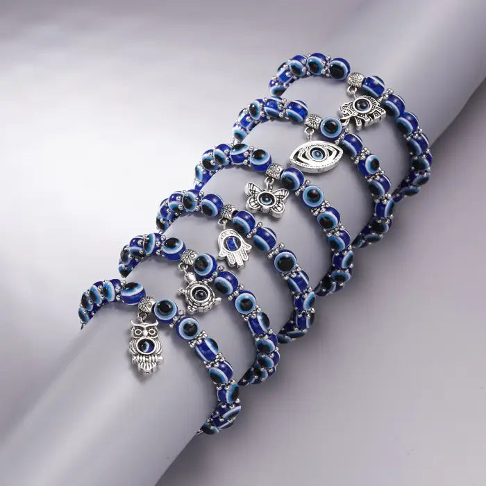 Stack of blue evil eye bracelets with silver charms for Turkish protection and positive energy.