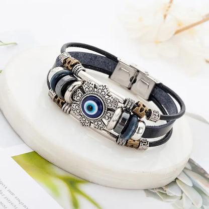 Stylish blue evil eye layered bracelet with leather straps and intricate metallic charm design.